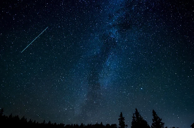 Bright shooting star streaking across a sparkling night sky filled with stars and the Milky Way, creating a magical and dreamy stargazing scene.